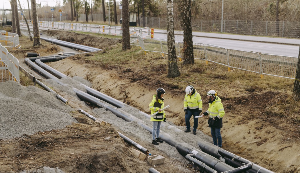 Personer i gula varselkläder inspekterar ledningsarbeten. 