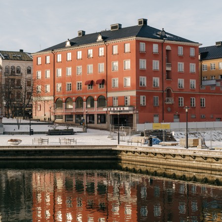 Kvarteret Castor i Södertälje, röd flervåningsbyggnad som ligger vid vattnet.