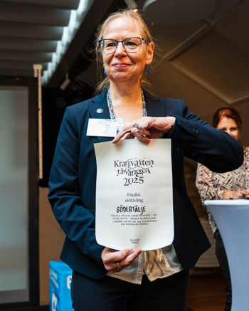 En kvinna håller upp en skylt framför en folkmassa.