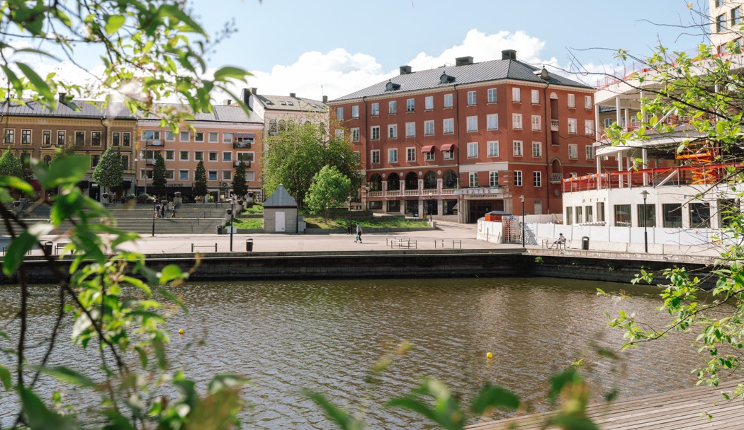 En flod som rinner genom en stad bredvid höga byggnader.