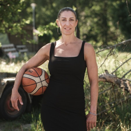 Kvinna i svart klänning poserar med en basketboll under armen