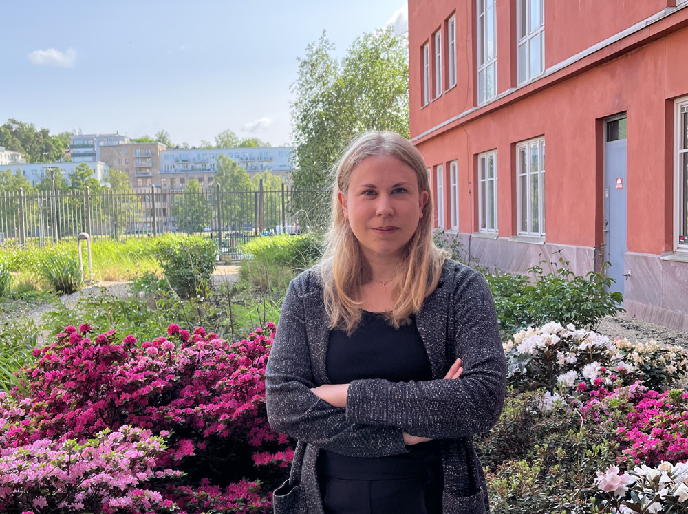 En kvinna som står framför några blommor.