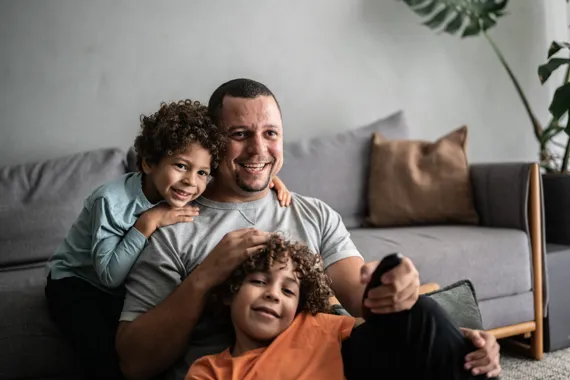 En man och två barn sitter i en soffa.