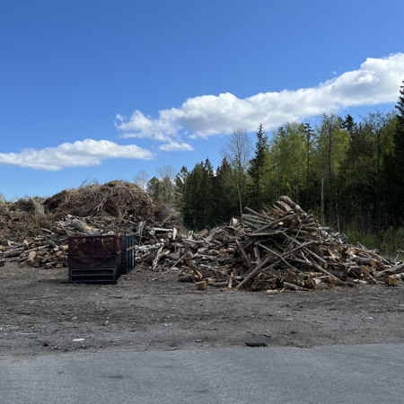 En hög med trä som ligger vid sidan av en väg.