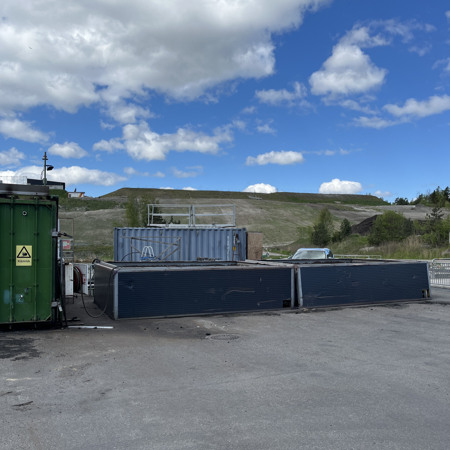 En grön fraktcontainer som står på en parkeringsplats.