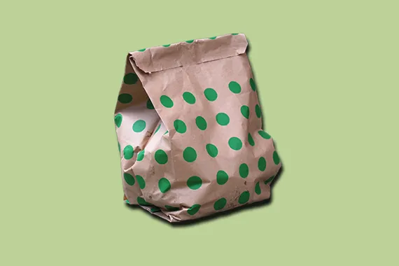 Brun papperspåse med gröna prickar mot en grön bakgrund.