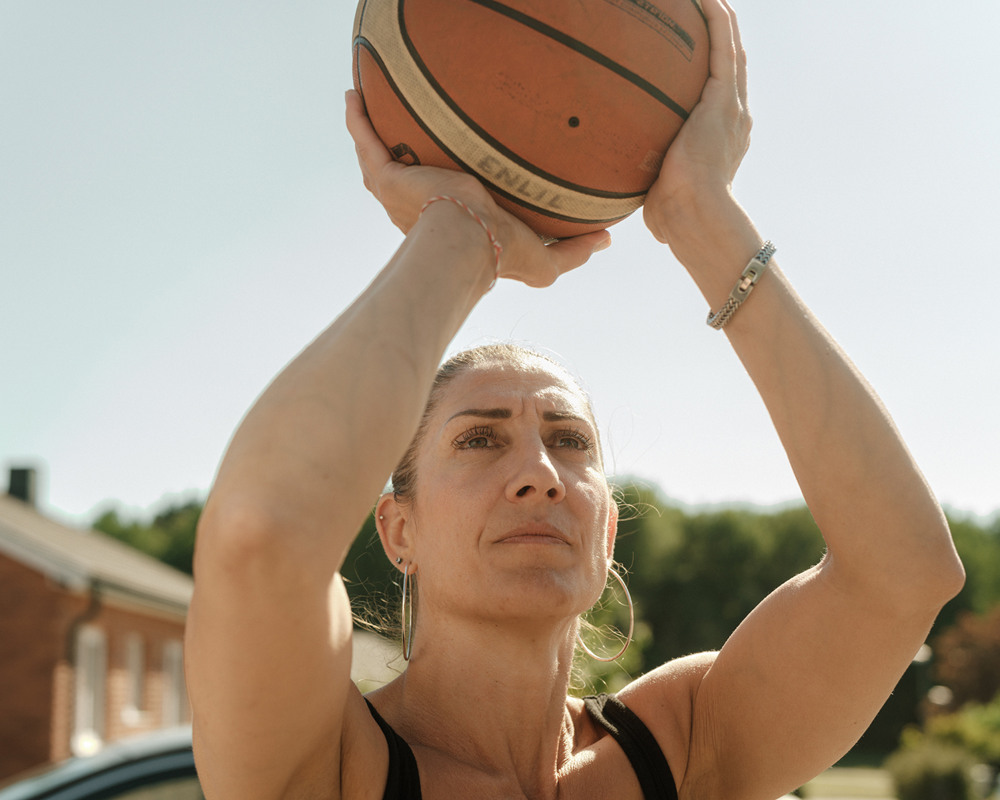 Kvinna som håller en basketboll ovanför huvudet.