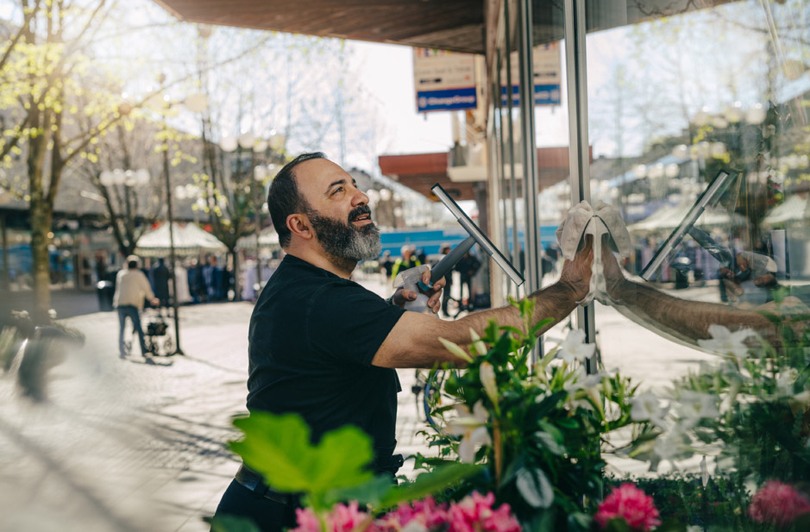 En man som putsar fönster på en blomsteraffär