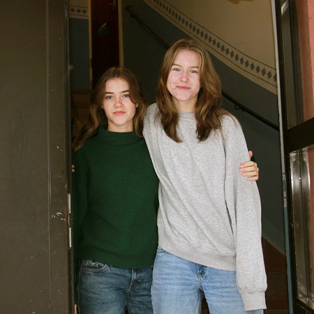 Två tonårstjejer står i en portöppning