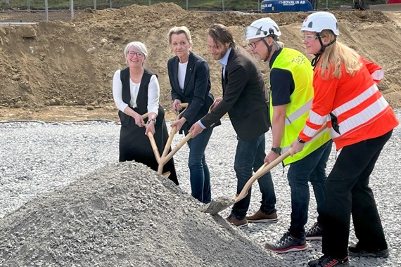En grupp människor som står runt en jordhög.