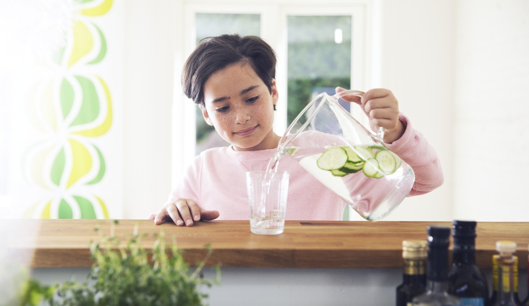 Ett barn häller upp vatten i ett glas