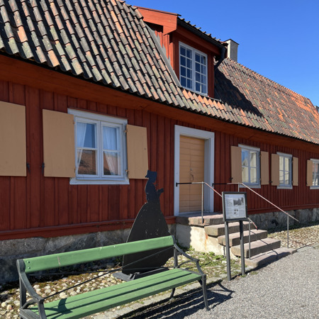 En grön bänk framför en röd byggnad.