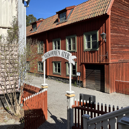 En röd träbyggnad med en vit skylt framför.