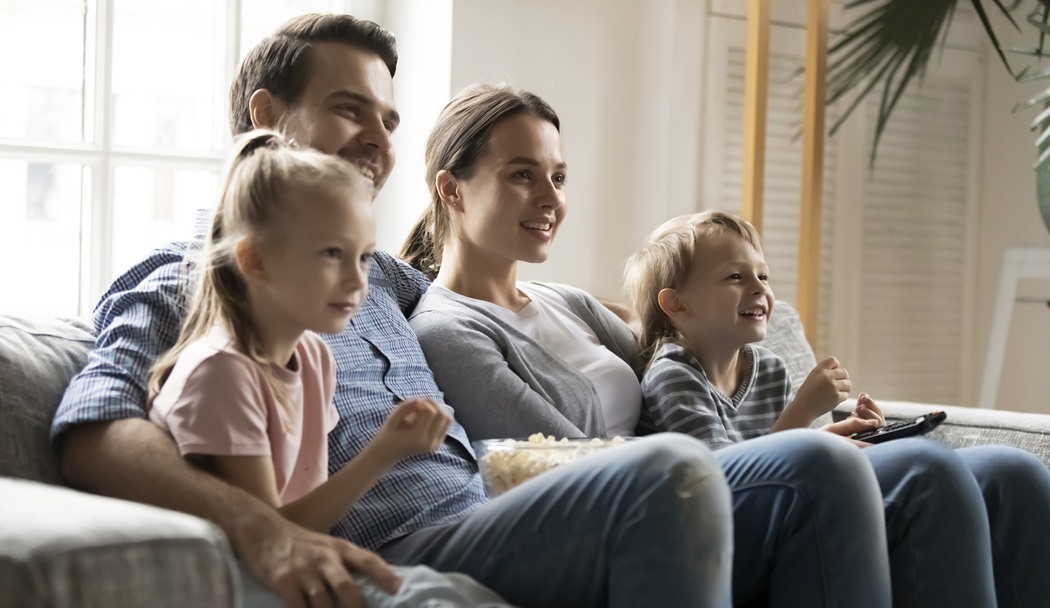 En man och en kvinna sitter tillsammans med två barn i en soffa. 