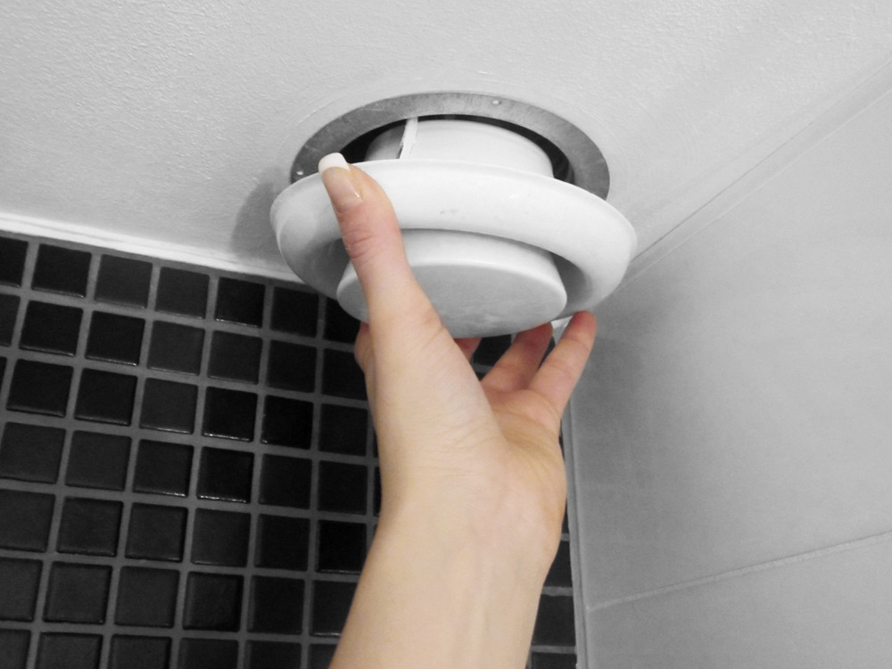 Hand som drar loss ett ventilationsdon i badrummet