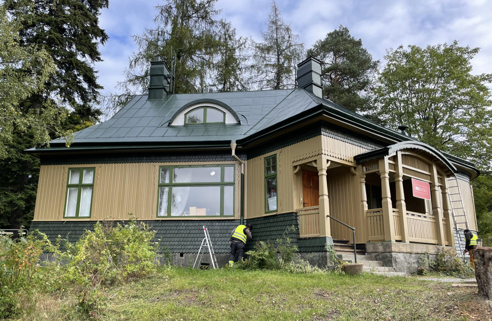En trävilla med grönt tak restaureras.